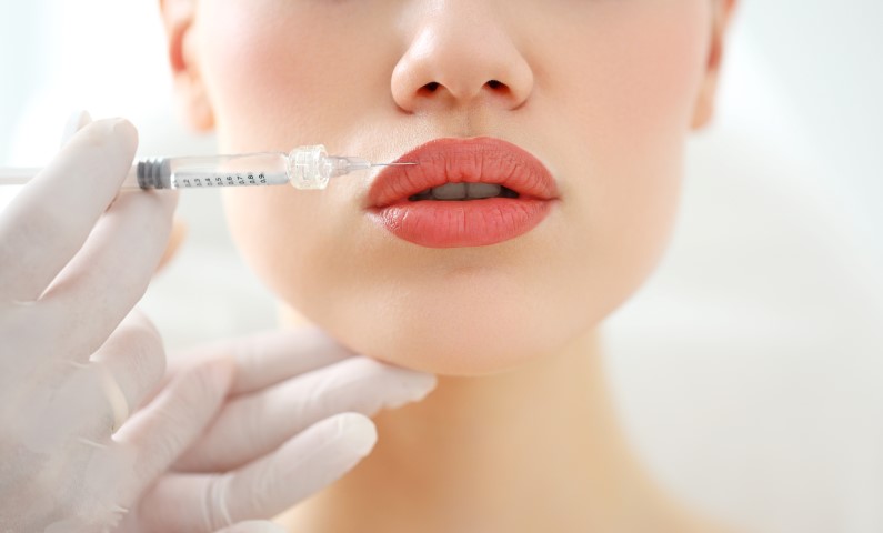 Woman receiving beauty injection in lips