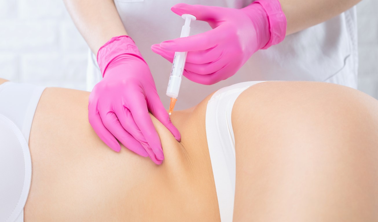 A doctor of aesthetic cosmetology makes lipolytic injections to burn body fat on a woman”u2019s stomach and body. Female aesthetic cosmetology in a beauty salon.